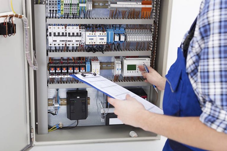 Technician Holding Clipboard While Examining Fusebox